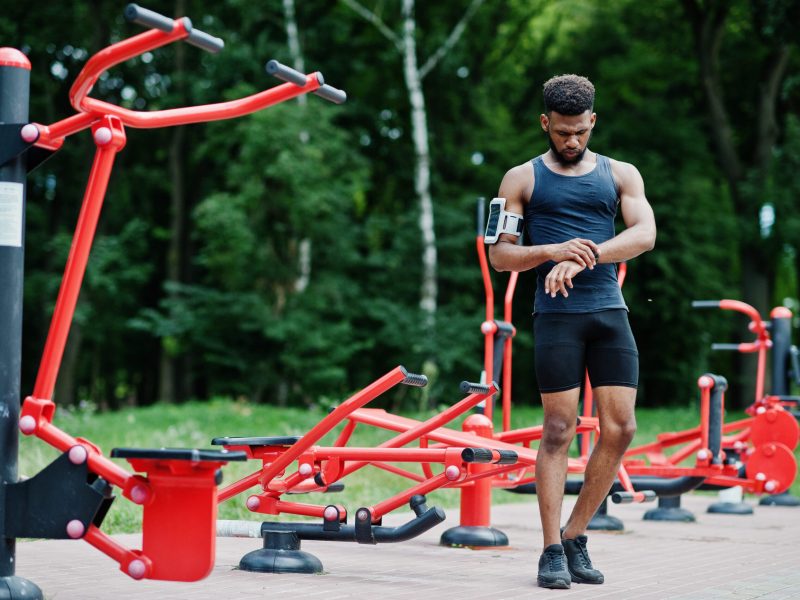 african-american-male-athlete-sport-man-with-running-sports-arm-case-for-mobile-phone-posed-against-street-workout-simulators (1)